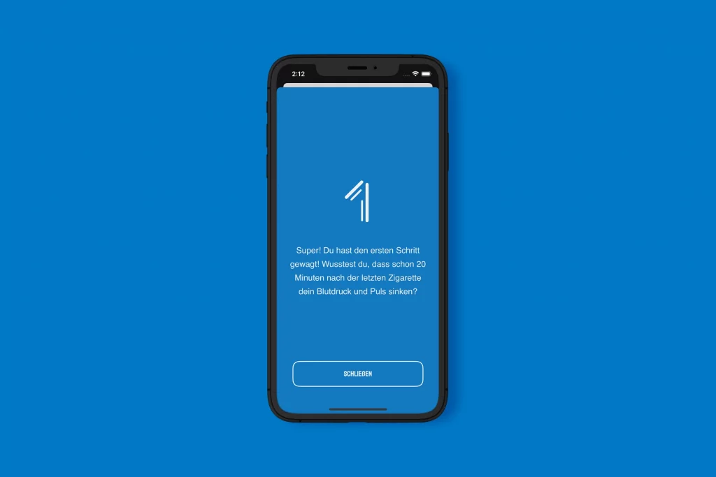 Motivationsbildschirm der "AntiSmokeApp" auf einem Smartphone mit dunkelblauem Hintergrund. Im oberen Bereich ist eine große, weiße, stilisiertes Eins zu sehen. Darunter steht der Text: "Super! Du hast den ersten Schritt gewagt! Wusstest du, dass schon 20 Minuten nach der letzten Zigarette dein Blutdruck und Puls sinken?". Am unteren Rand befindet sich ein weiß umrandeter Button mit der Aufschrift "SCHLIESSEN".